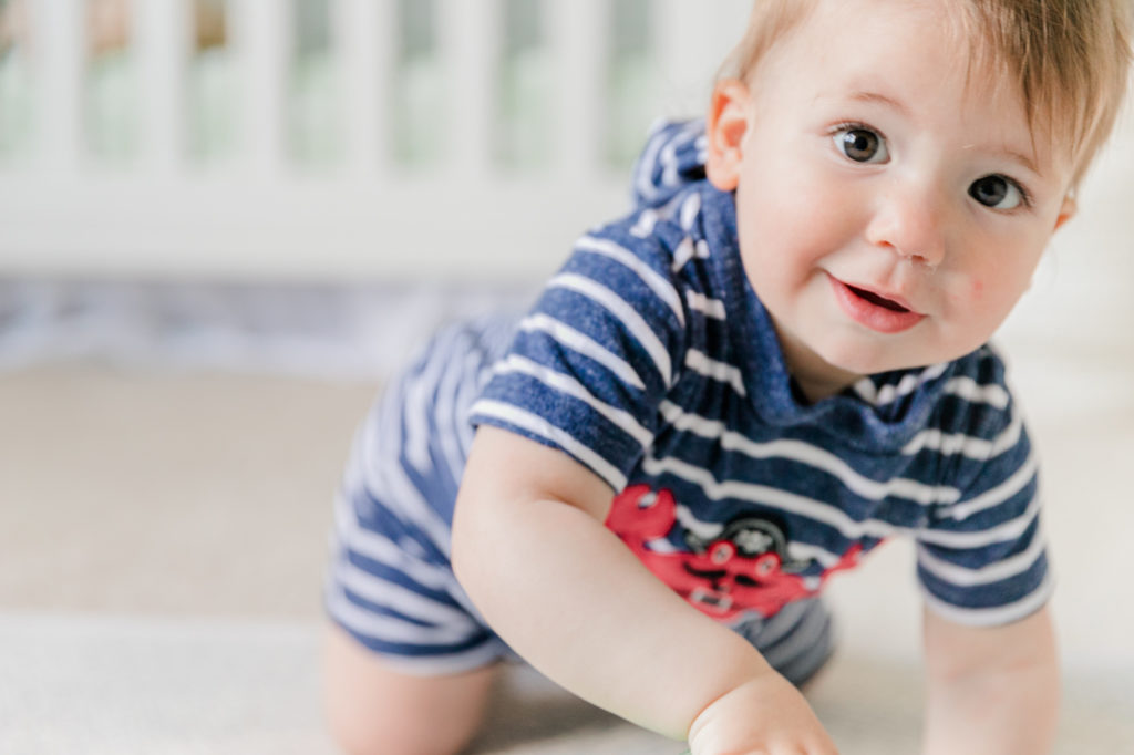Young child crawling toward camera with smile