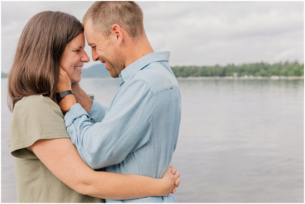 Couple holding each other close and smiling in front of lake