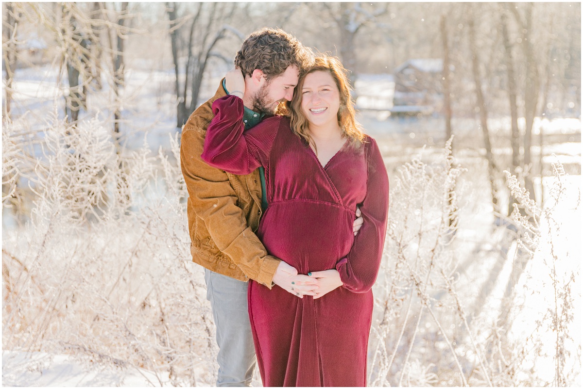 Snowy maternity photo of smiling mom and dad