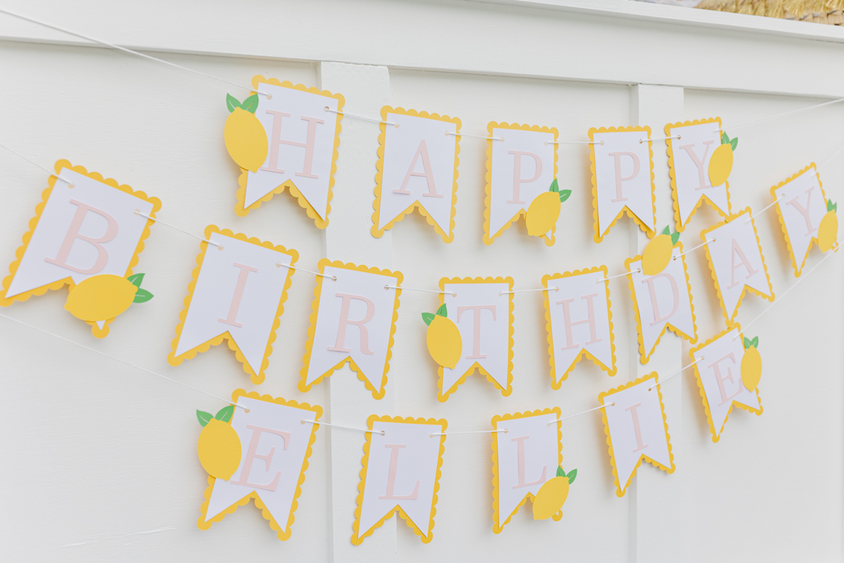 Banner with flags spelling out "Happy Birthday Ellie" with lemons on several flags for a lemonade themed birthday party
