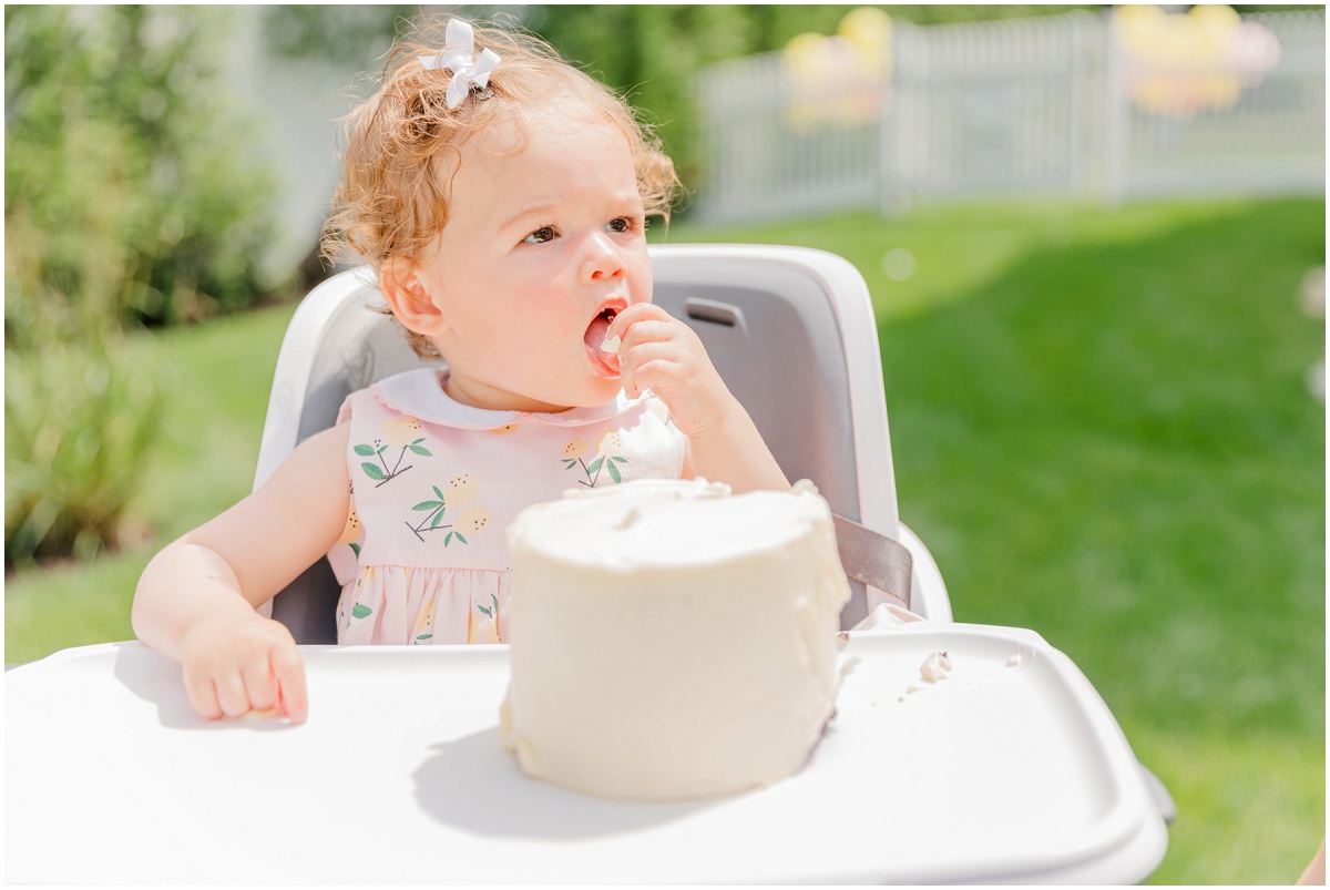 One-year-old in high chair tasting smash cake frosting