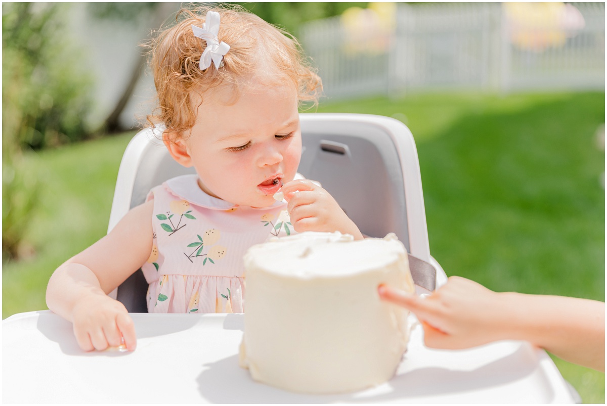 One-year-old in high chair tasting smash cake frosting
