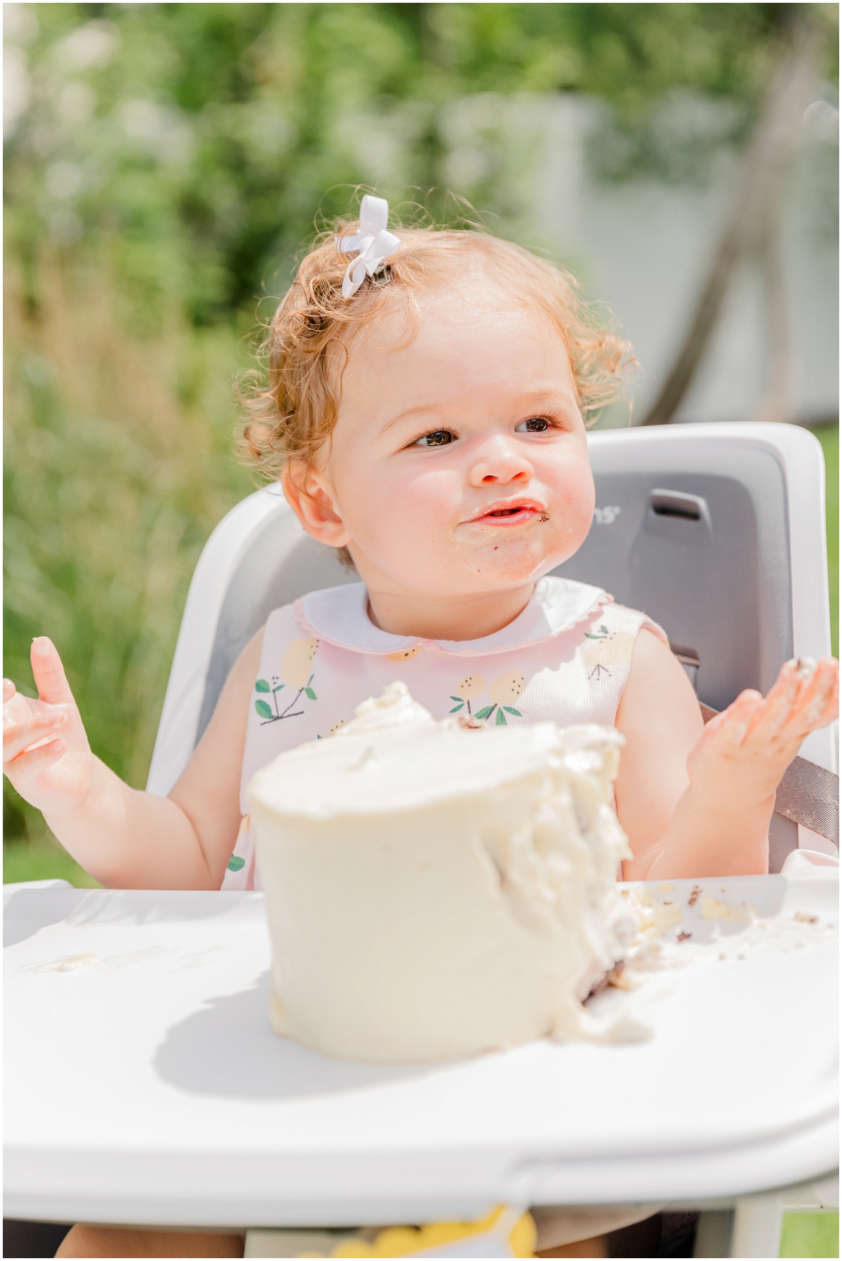 messy one-year-old smiling behind smash cake