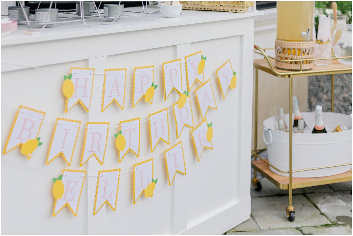Hanging lemon flags that spell "HAPPY BIRTHDAY ELLIE" next to a drink cart