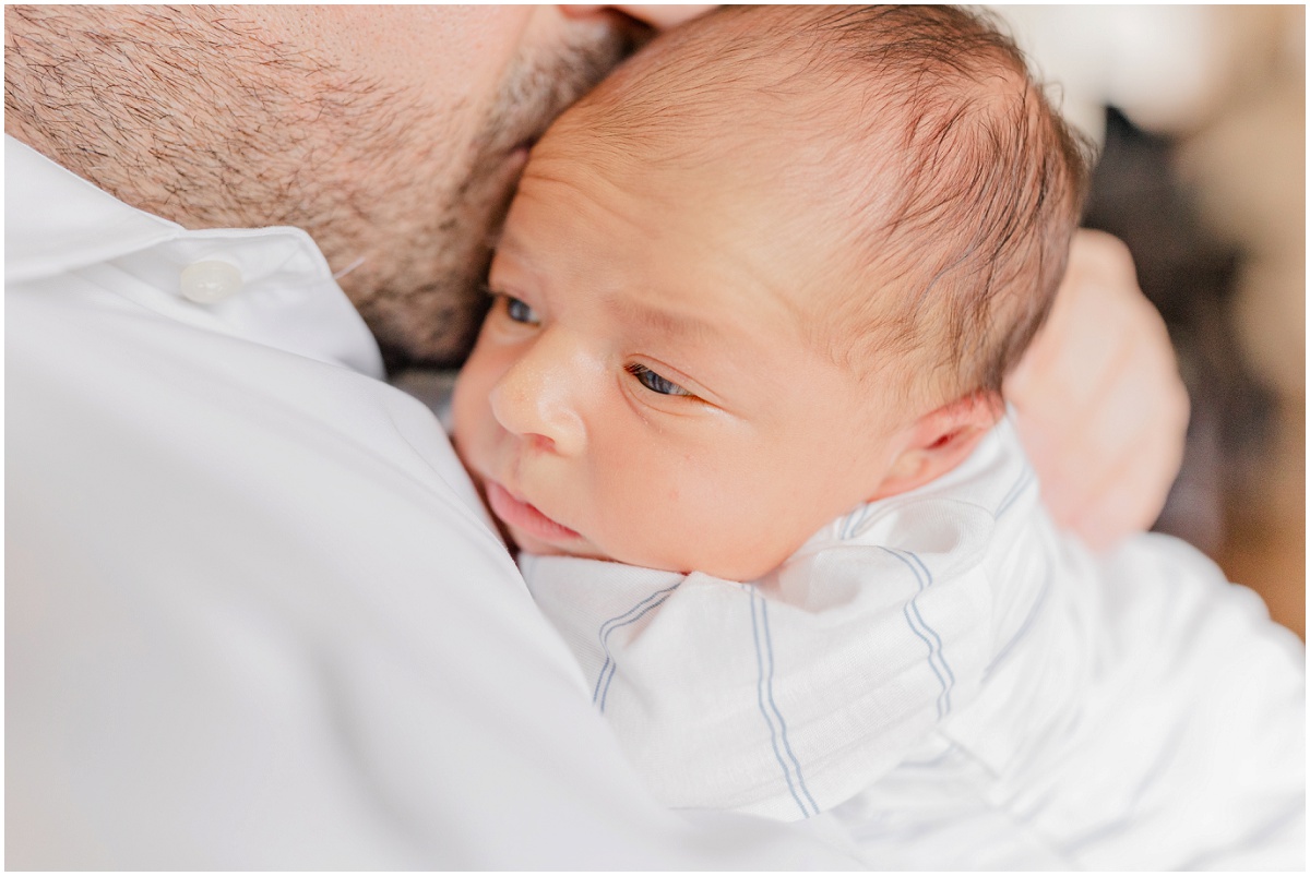 Newborn with eyes open looking over dad's shoulder
