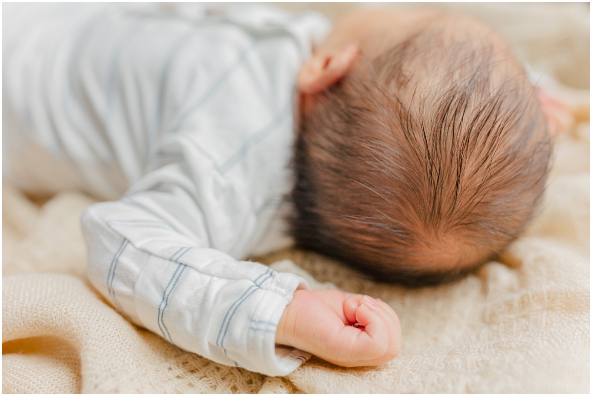 Detail photo of sleeping newborn's hand behind back of newborns head