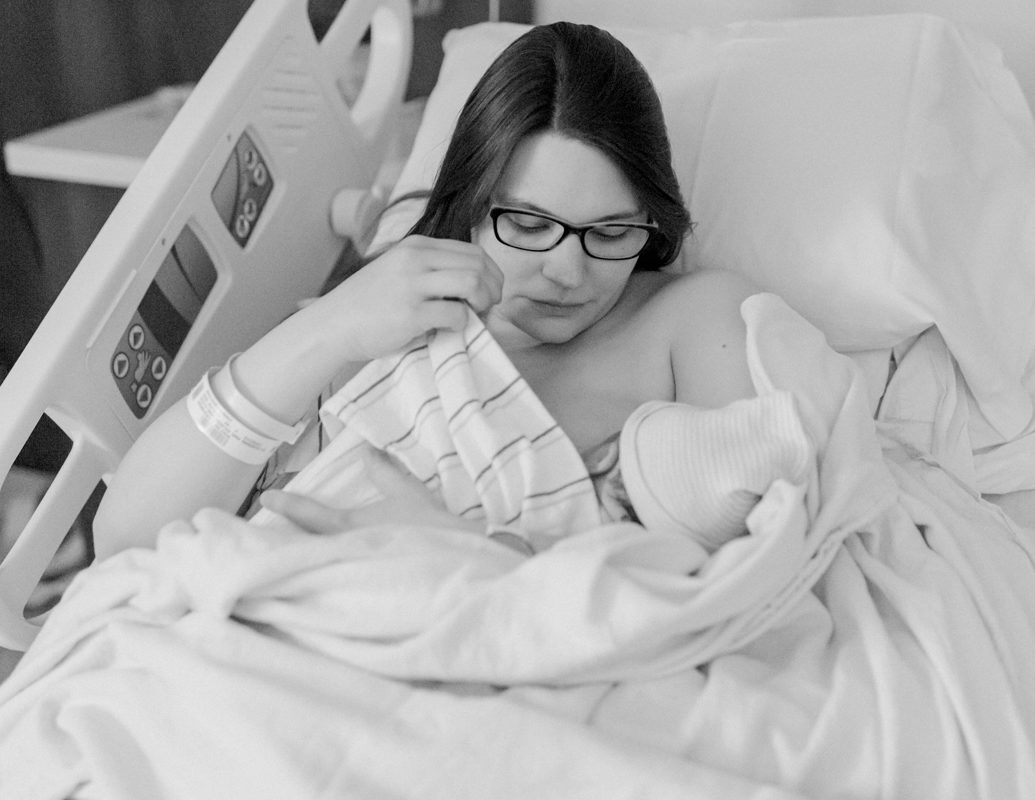 Black and white image of other in hospital bed holding just born baby delivered by AFA Concord midwives