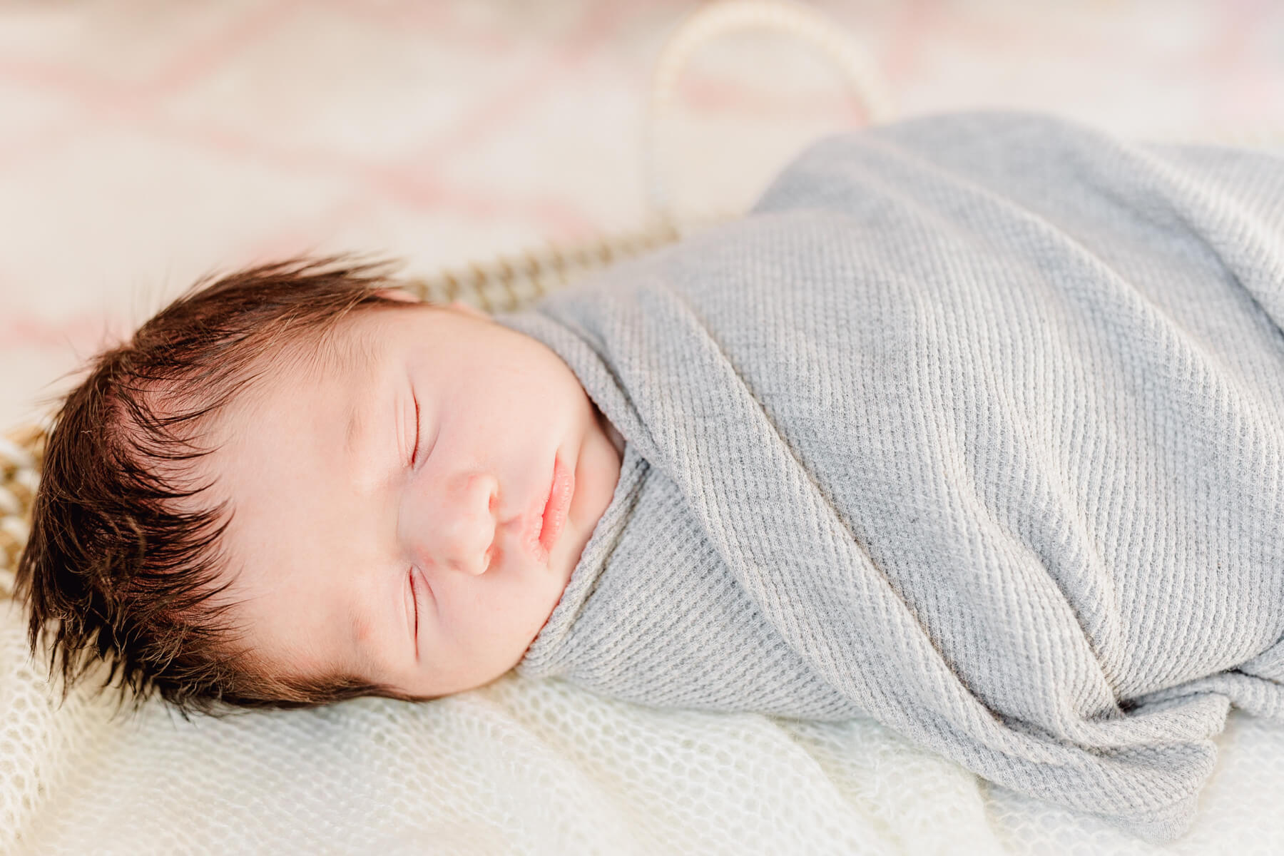 When to Do Your Newborn Photos: Example of a 2-week old baby sleeping snuggly in a grey blanket