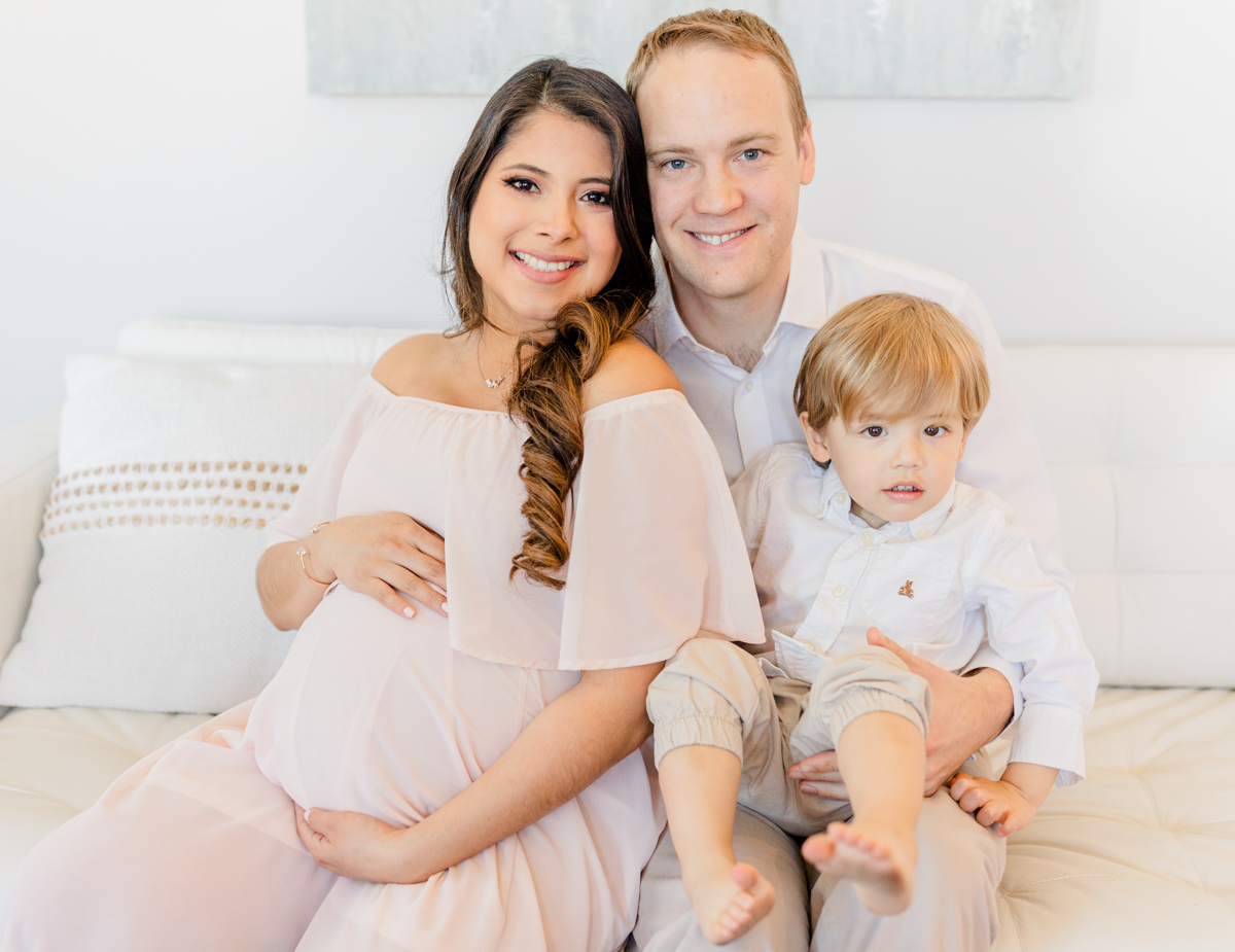 Boston Prenatal Massage - Pregnant mother, her husband, and their toddler son sit together on the couch