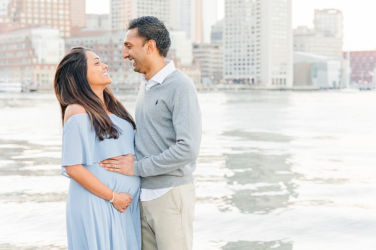Pregnant Boston mother and father laughing with city skyline in the background
