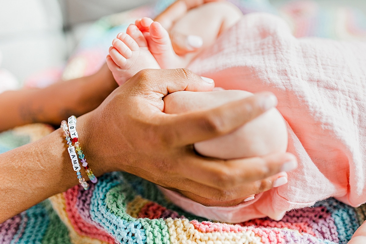 close up of mom's hands embracing newborn's legs and feet