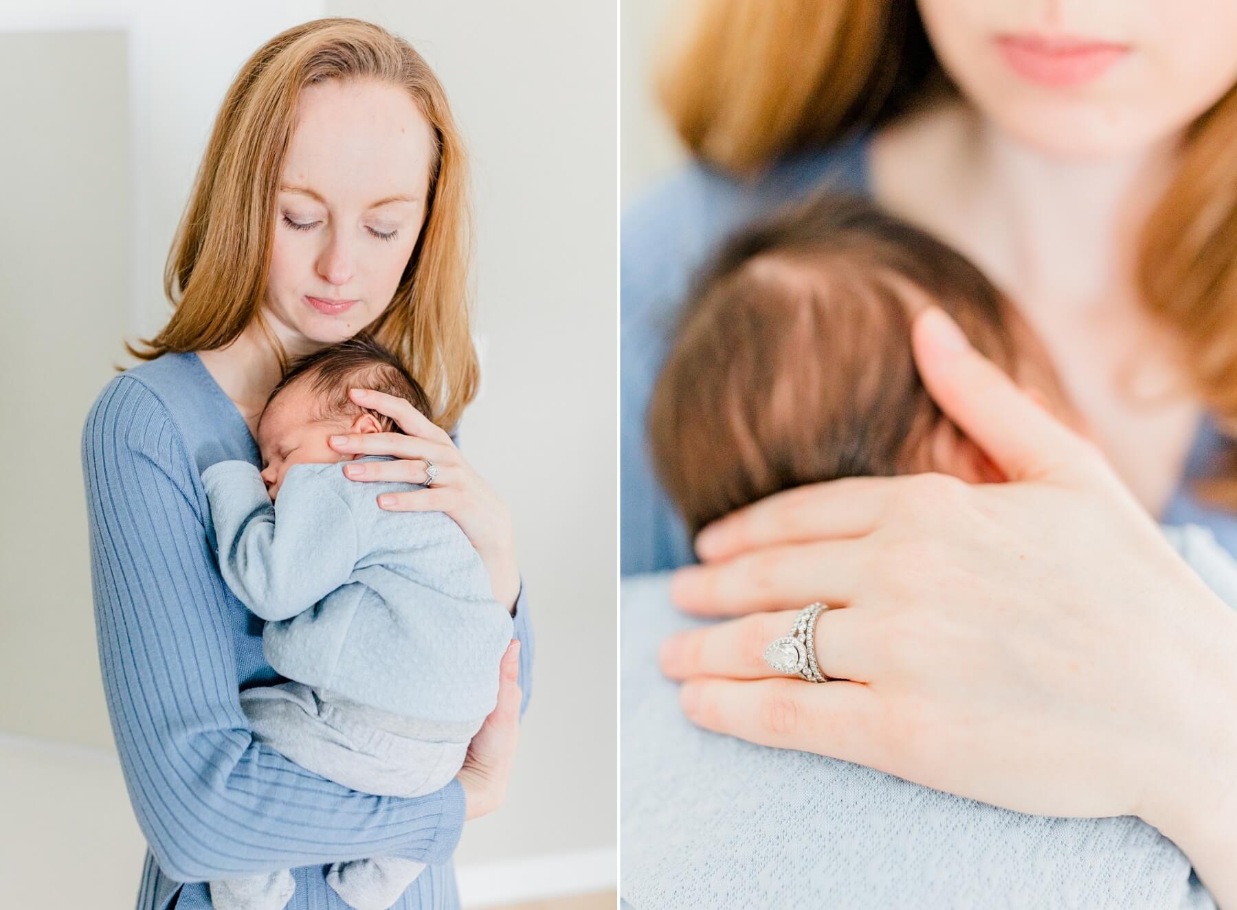 A mom in a blue dress stands in a studio cradling her sleeping newborn baby against her chest